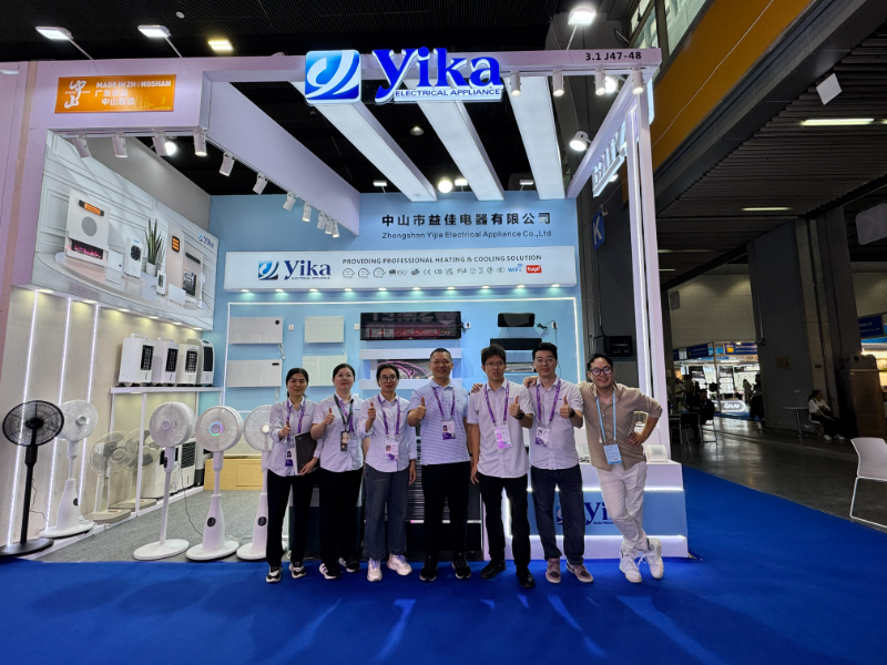 Yika team giving thumbs up at their Canton Fair 2026 booth displaying electric fans and heating solutions.