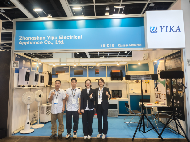 YIKA team members posing at their booth with appliances like fans and heaters at the Hong Kong Electronics Fair.